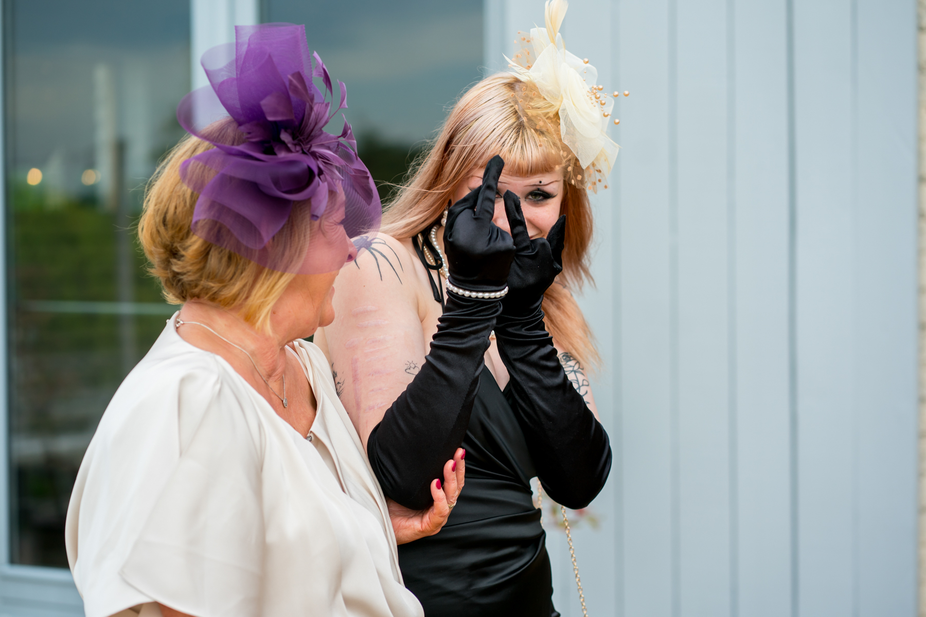 Two women wearing fascinators at outdoor event
