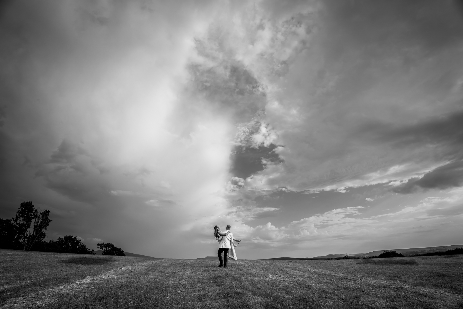 Couple in open field beneath dramatic sky