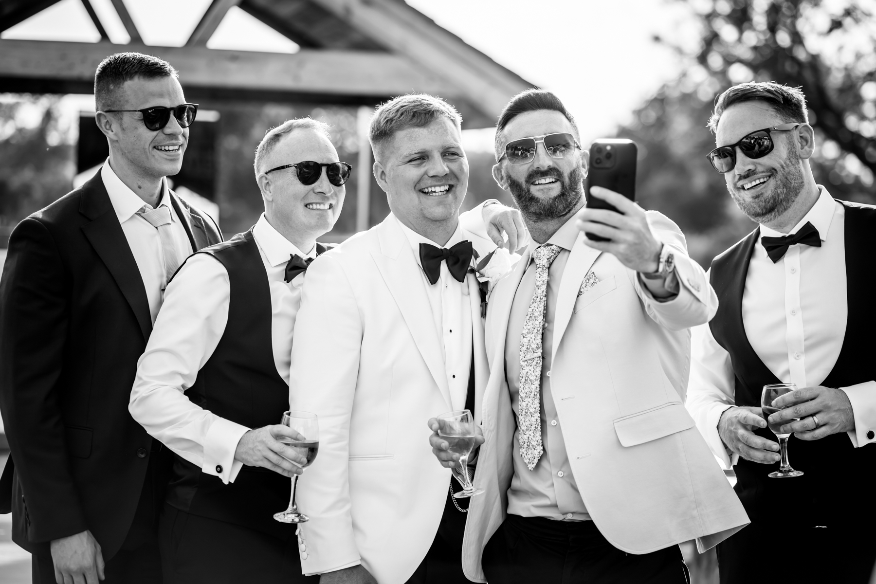 Groom and groomsmen taking selfie outdoors