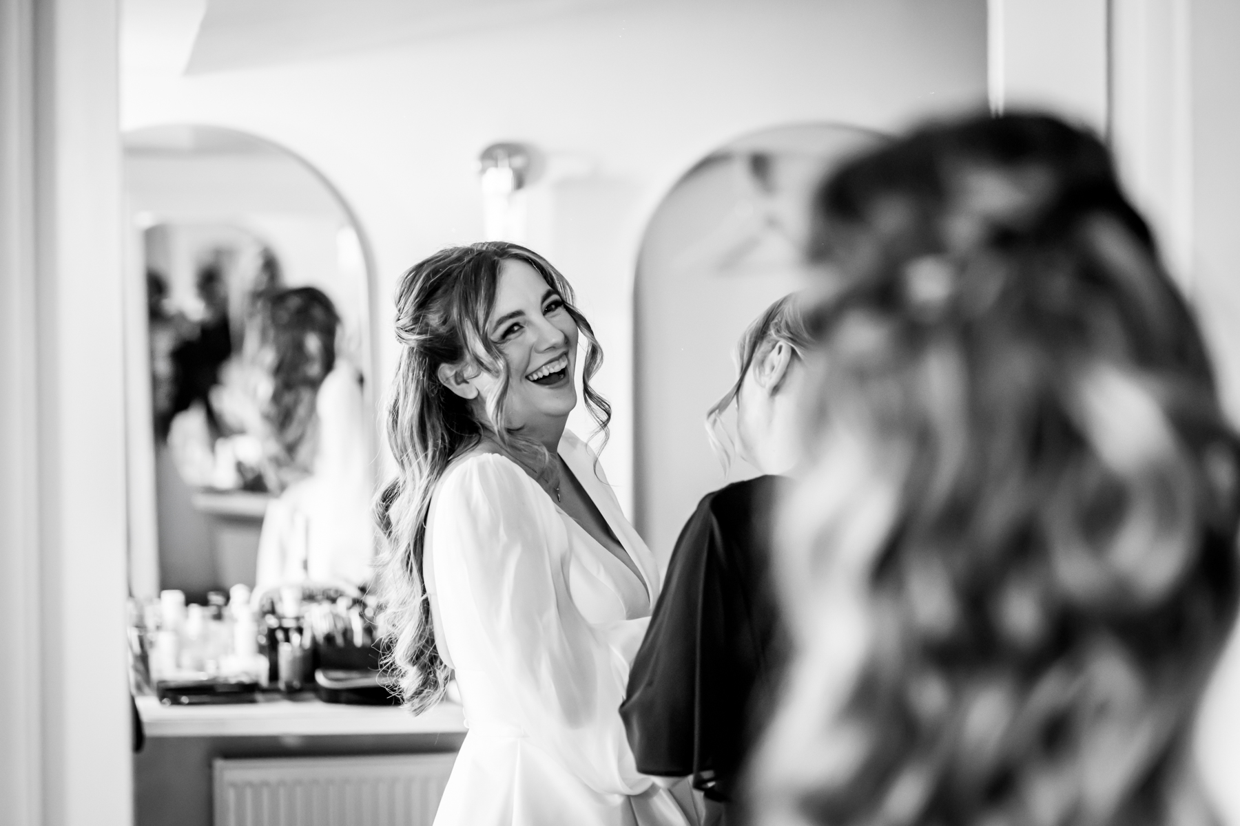 Bride laughing while getting ready with stylist