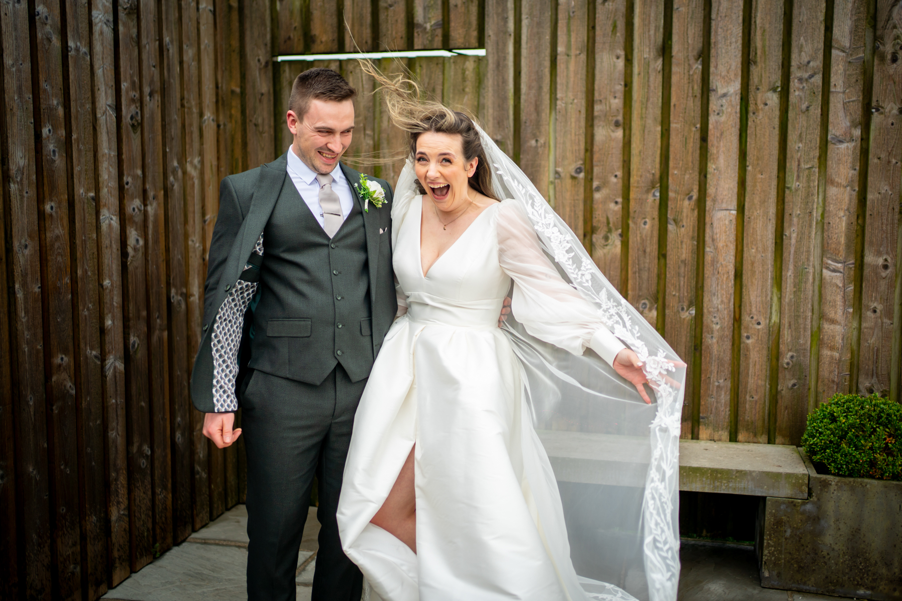 Bride and groom laughing outdoors on wedding day