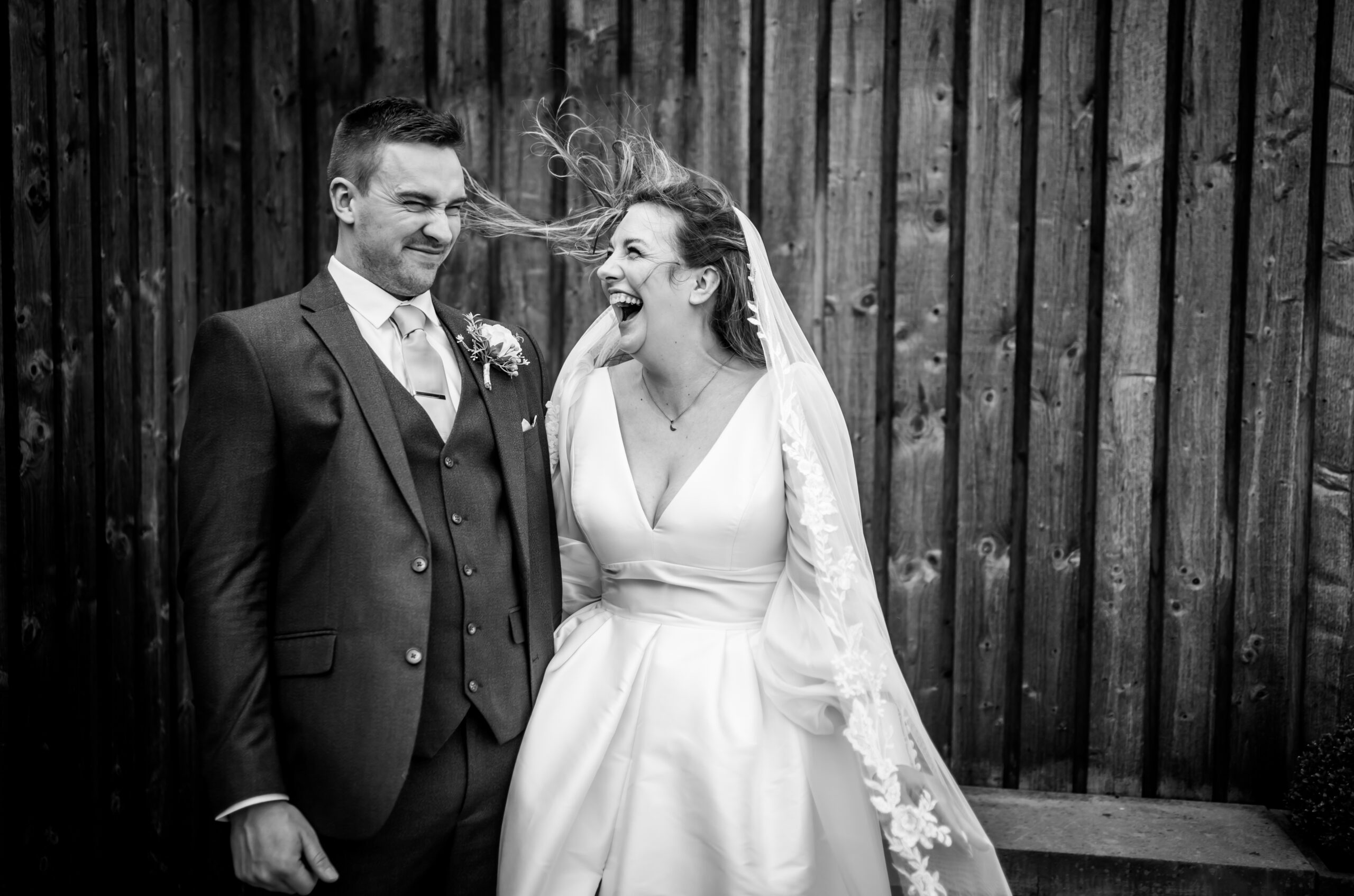Bride laughing as wind blows hair into groom