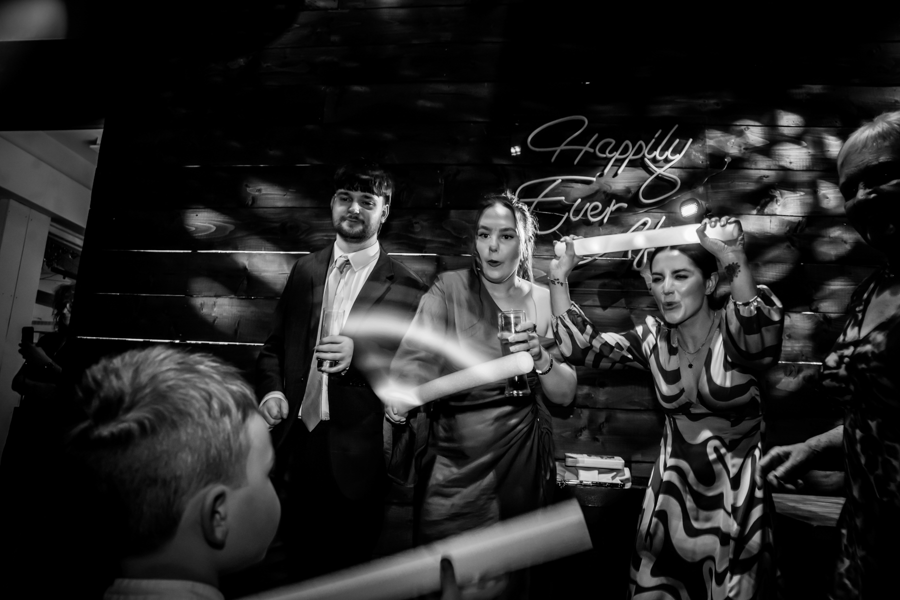 Wedding guests waving foam sticks on dancefloor