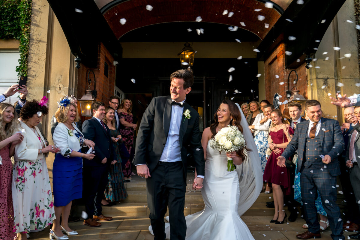 Bride and groom walking through confetti outside venue
