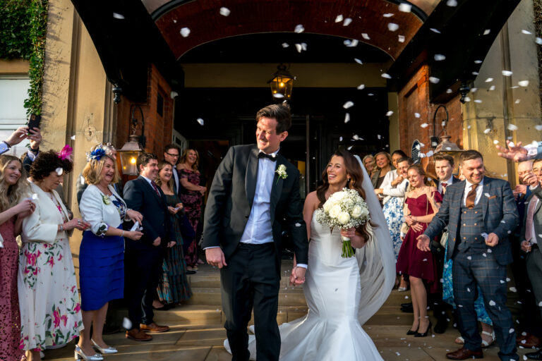 Bride and groom walking through confetti outside venue