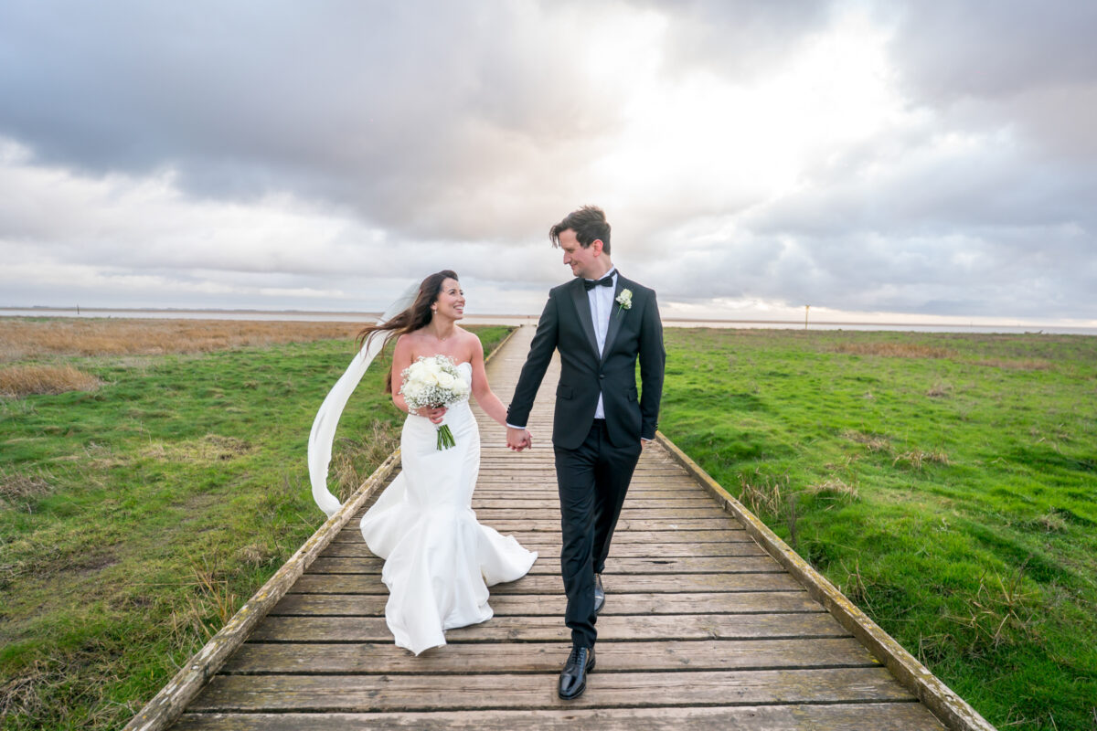 Bride and groom walking on countryside boardwalk
