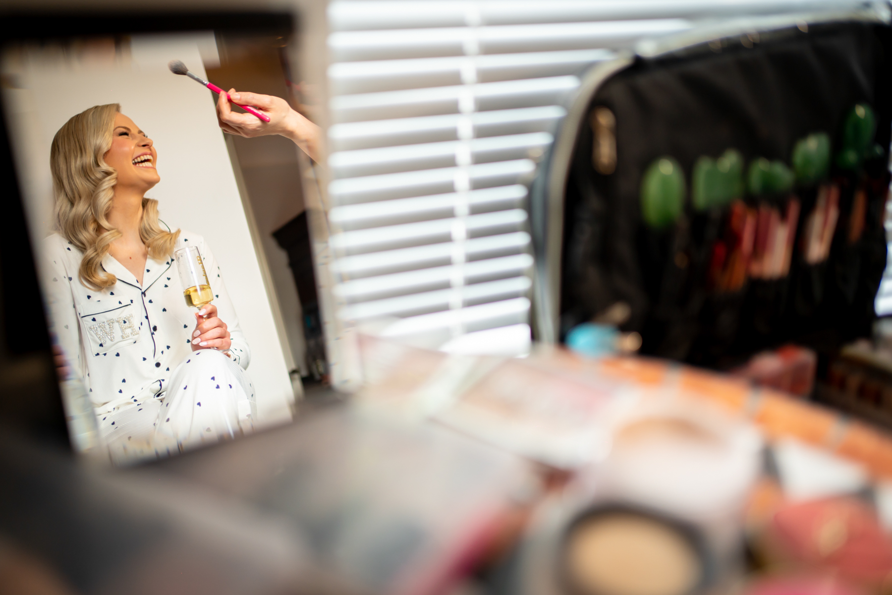 Woman laughing while having makeup applied indoors