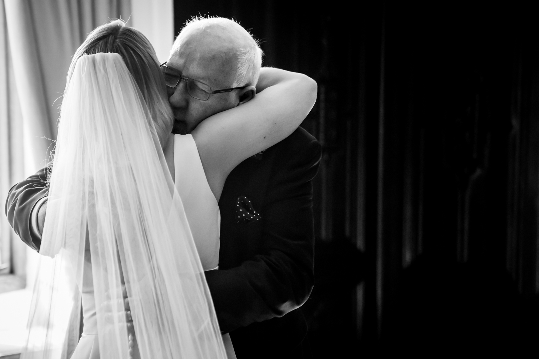 Bride embracing older man in emotional moment