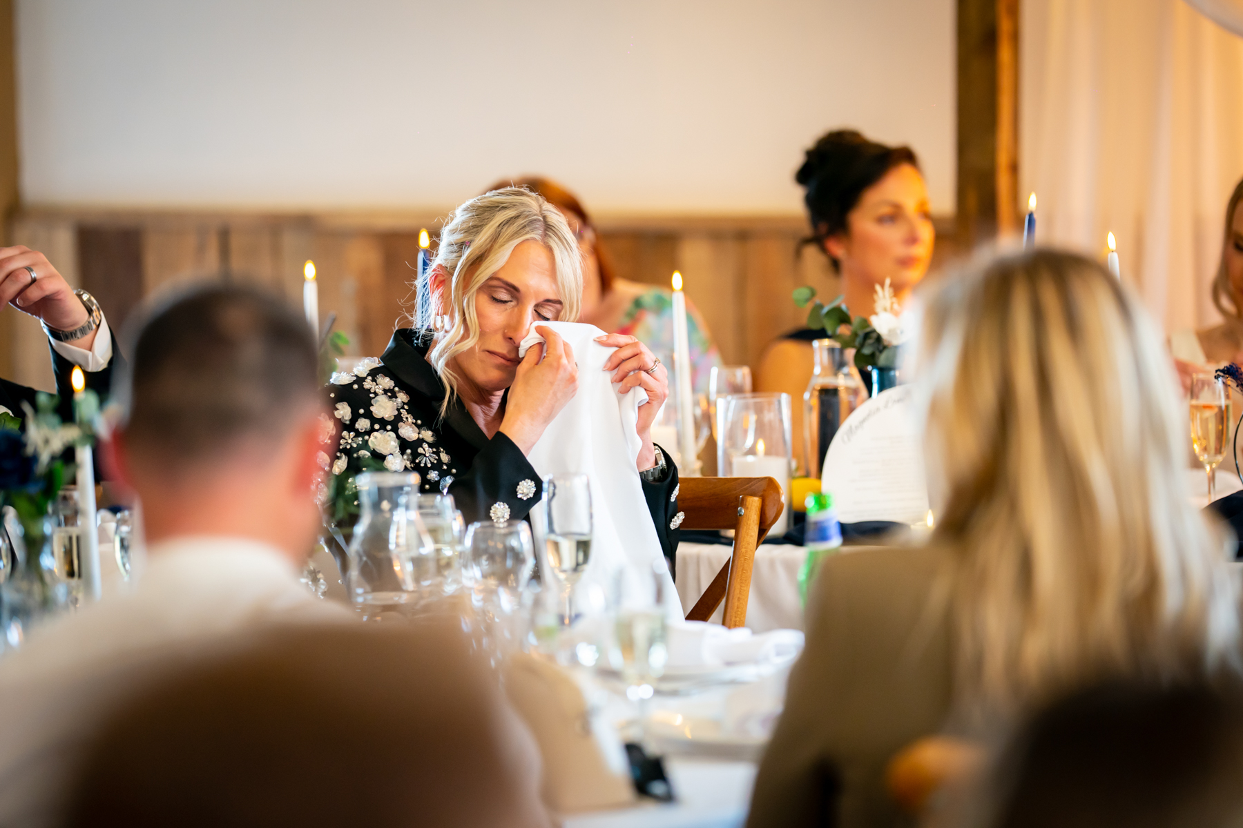 Woman wiping tears at candlelit wedding reception