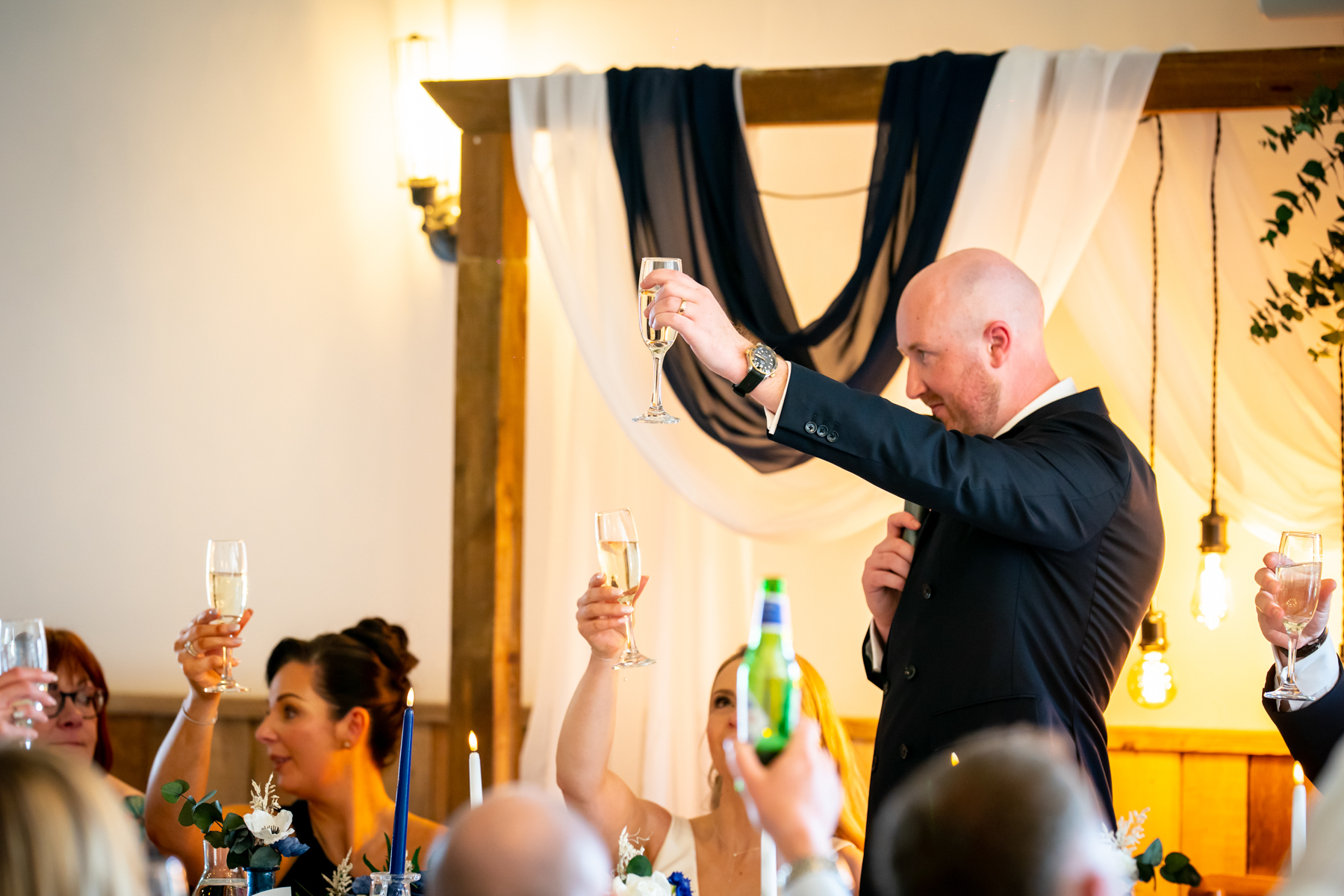 Man giving wedding toast with raised champagne glass
