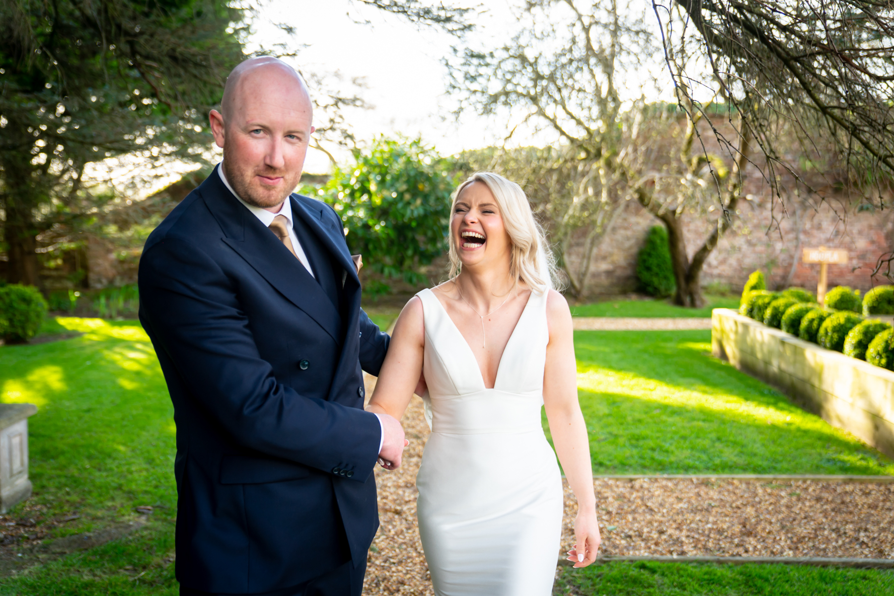 Bride and groom laughing in sunny garden
