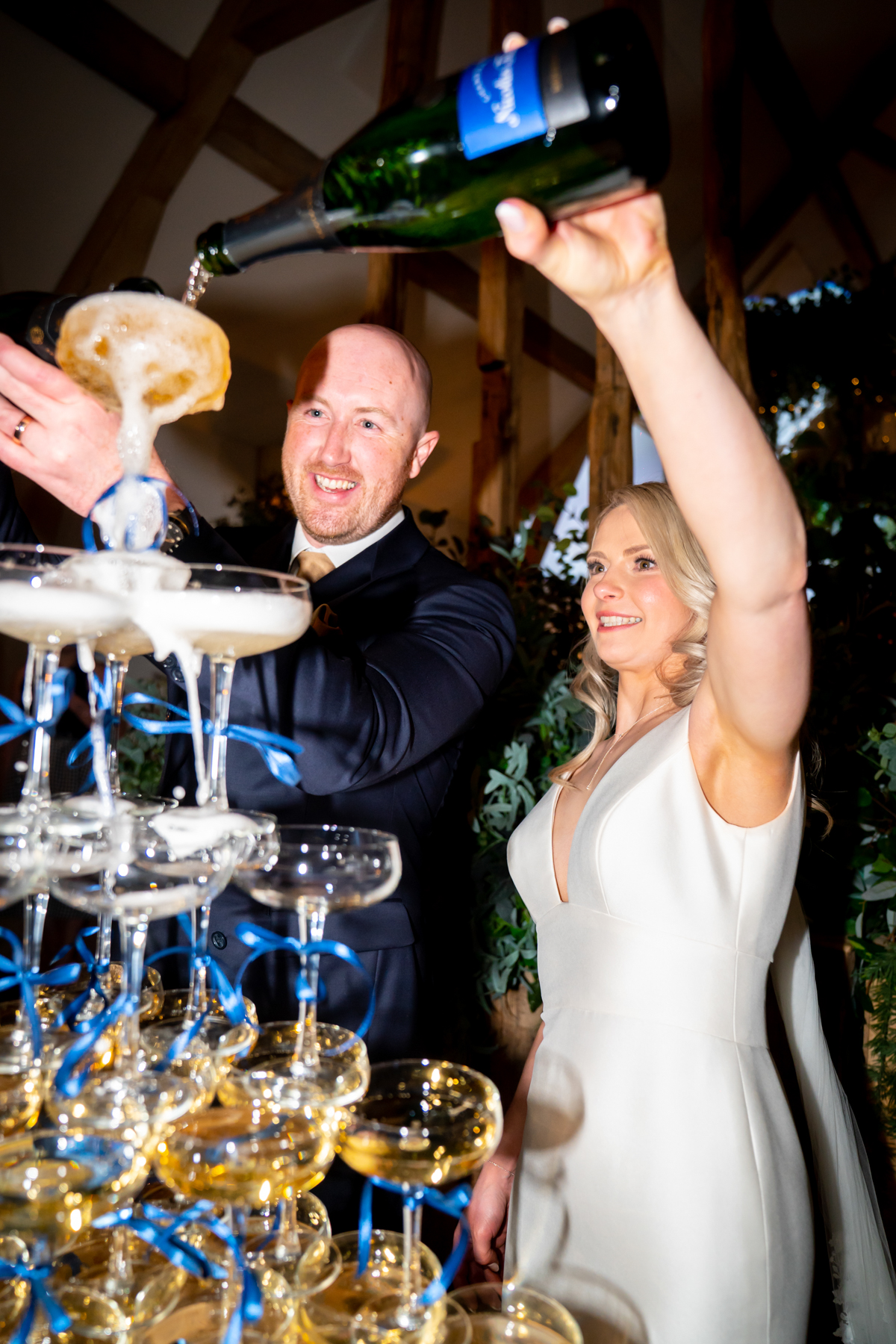 Couple pouring champagne into wedding champagne tower