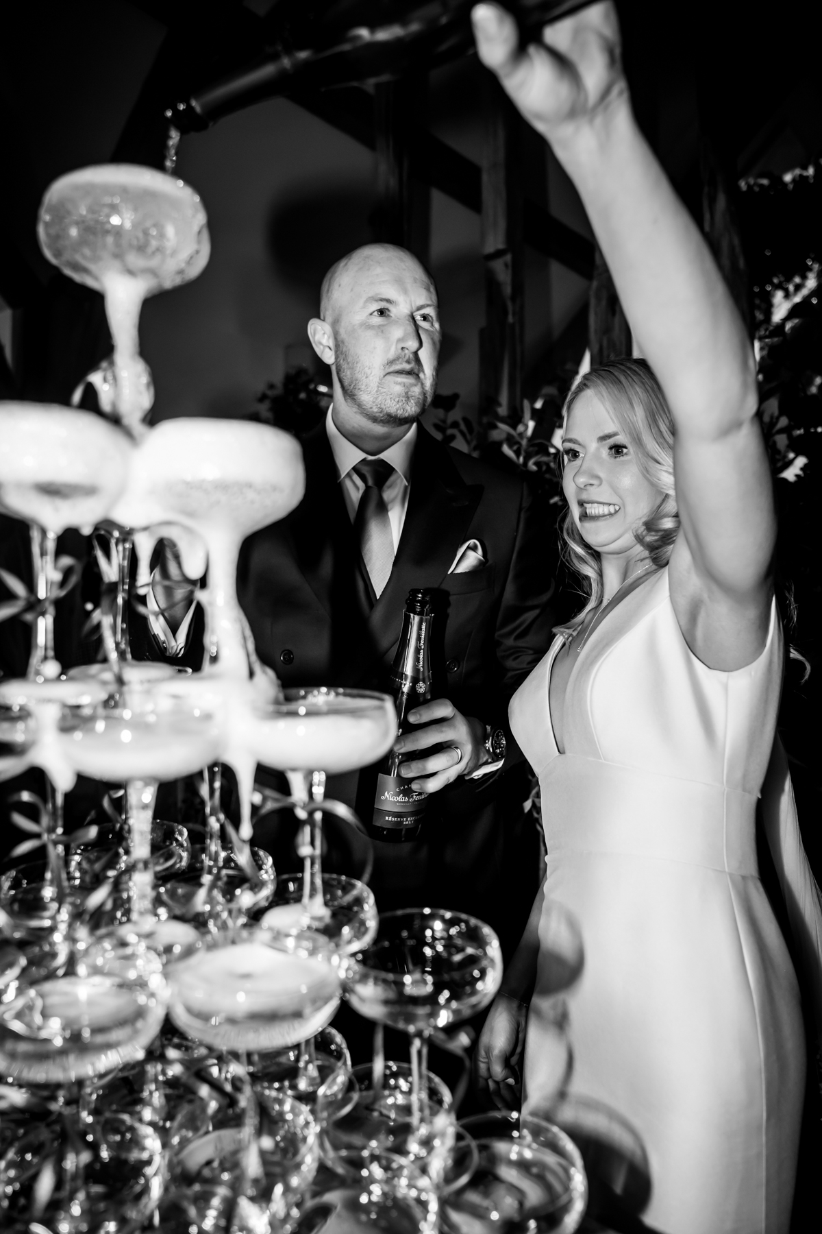 Bride and groom pouring champagne into glass tower