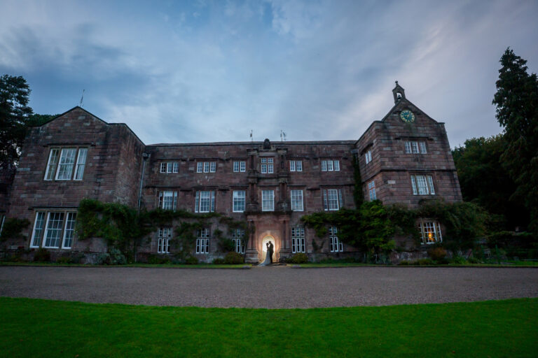 Wedding couple silhouetted in doorway of grand historic manor